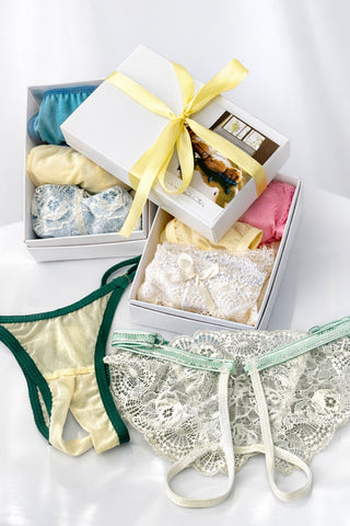 Secret Box NANIKA з жіночою білизною — мереживні трусики та подарункові коробки у різних кольорах, на світлому фоні.